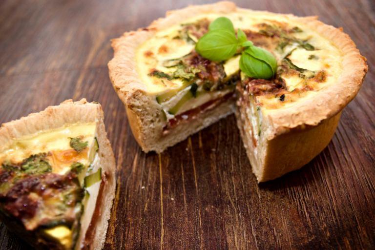 Eine köstliche, tief geschichtete mediterrane Quiche mit Basilikumbeilage